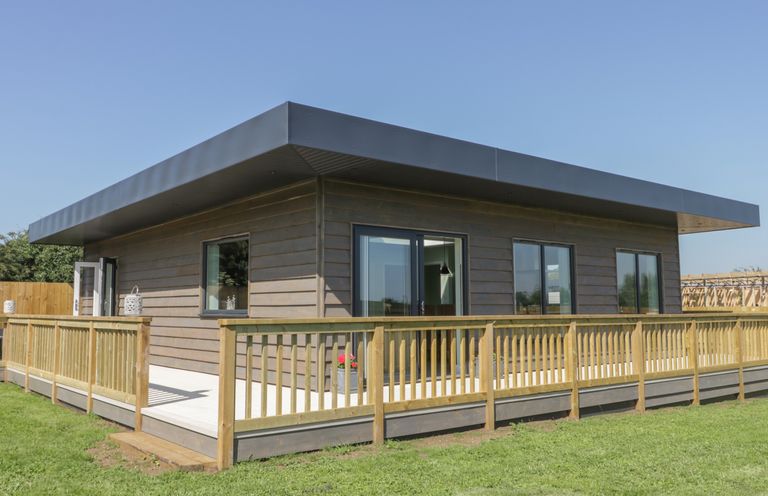 A single-story house with wooden exterior and railing on a lawn at Bluebell Wood in Brandesburton