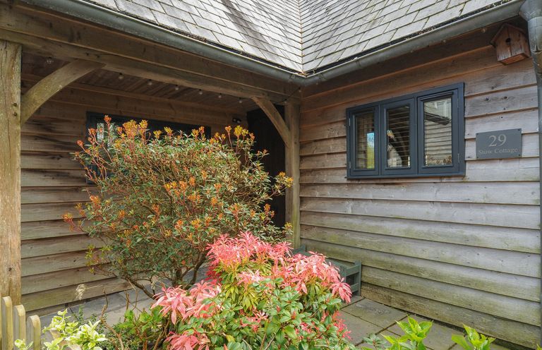 An entryway with wooden walls and roof with shrubs in front at Stow Cottage in Davidstow near Camelford