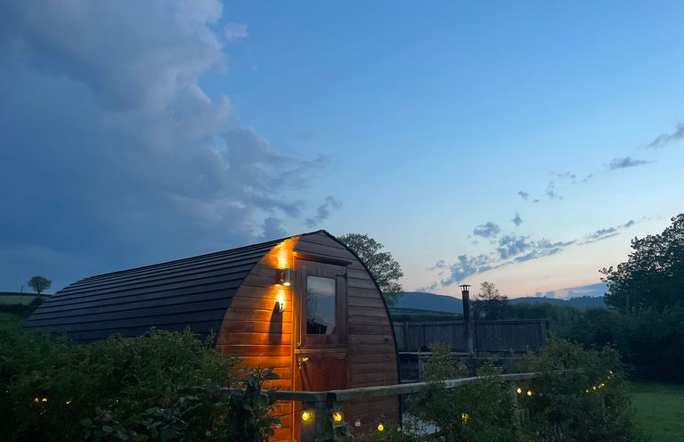 An outdoor cabin with lighting and trees at Embden Pod at Banwy Glamping Llanfair Caereinion