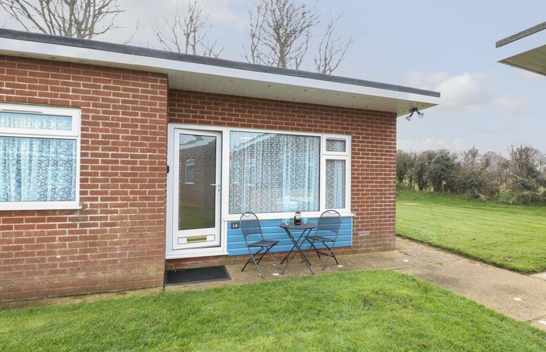 A small patio with a table and two chairs outside a brick house at 14 Siesta Mar in Mundesley