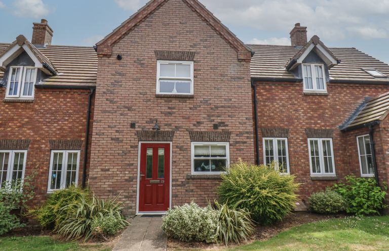 A house with a red door and windows at Buck Place The Bay - Filey