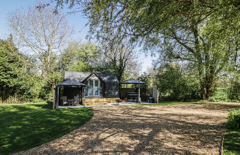 A cabin with a deck and seating area at Willow Lodge At Bridge Lake Farm & Fishery Chacombe