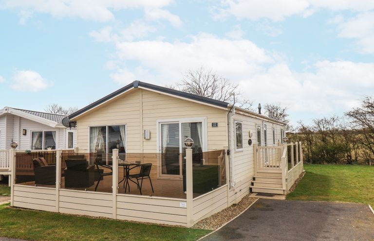 A single-story mobile home with enclosed porch furniture and a small driveway at Two Little Ducks in Cayton