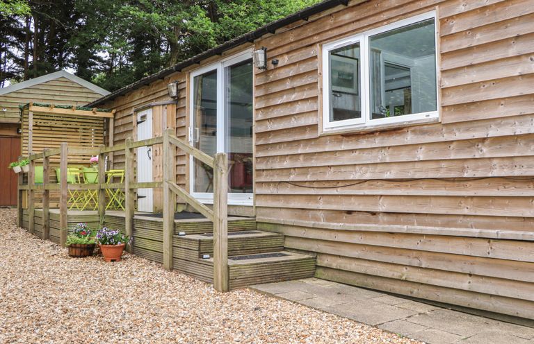 An outdoor area with steps leading to a wooden building at Orchard Lodge in Bolney