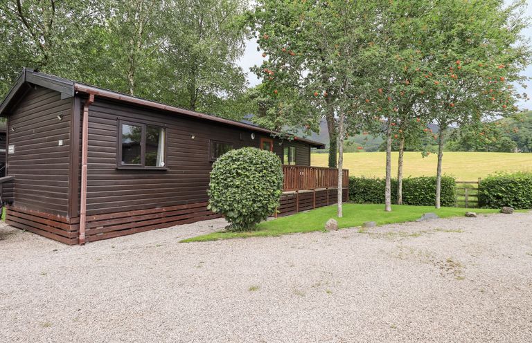 A cabin surrounded by trees and gravel area at Squirrels Leap Number 29, Burnside Park near Keswick