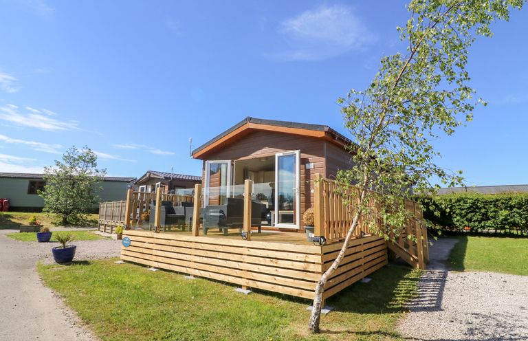 An exterior view of a wooden cabin with a patio area and outdoor furniture at Eden Lodge - Sherwood 21 in South Lakeland Leisure Village