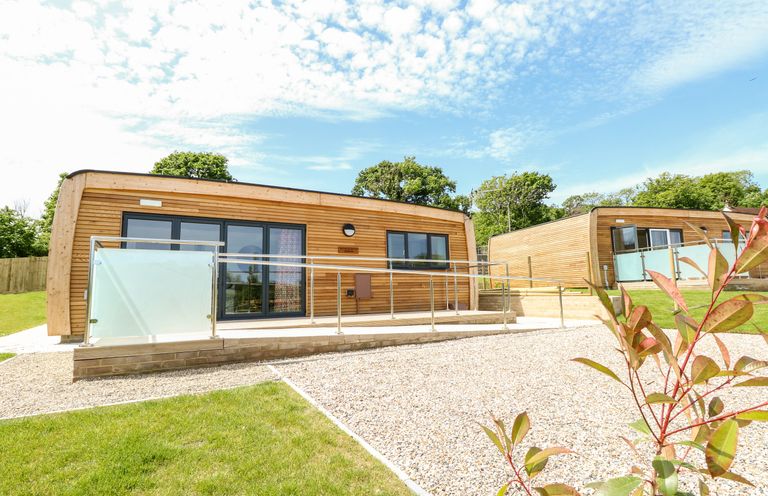Two wooden cabins with glass railings and gravel paths surrounded by grass and trees at Syrah in Seaview
