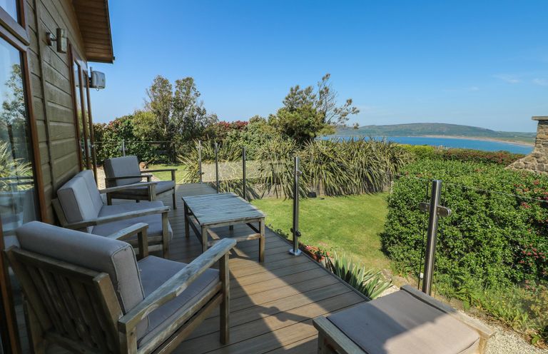 A deck area with wooden chairs and a table at Sunstone Lodge (Garreg Haul Lodge) Cilan near Abersoch