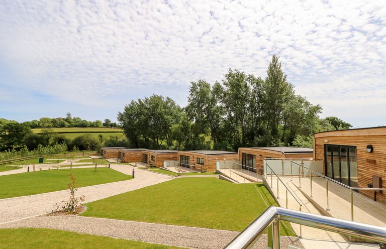 Wooden single-story cabins along walking paths with green grass and trees in the background at Chianti in Seaview