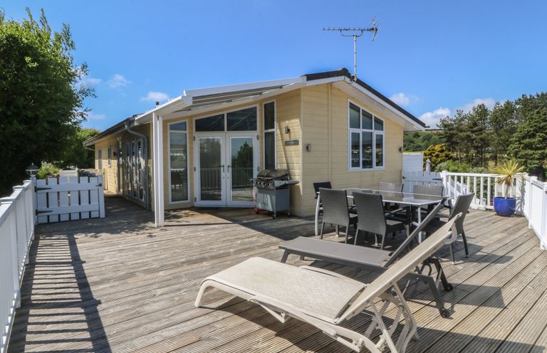 An outdoor patio with dining furniture and a grill at The Warren D26 in Abersoch