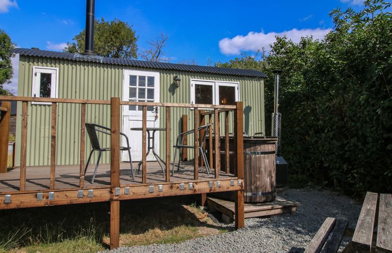 A hut with a wooden deck and hot tub at Aston - Shepherd Hut Aston On Clun