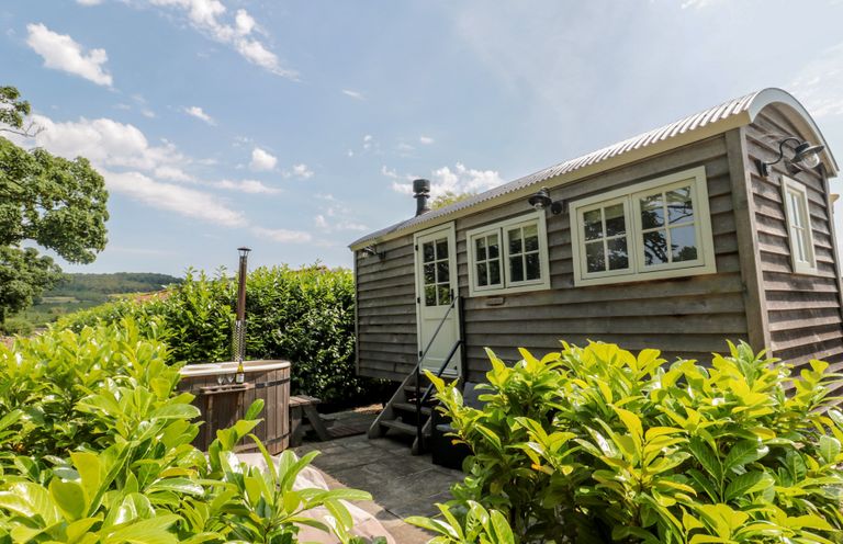 A wooden cabin with a hot tub and steps at Acorn in Bleadon