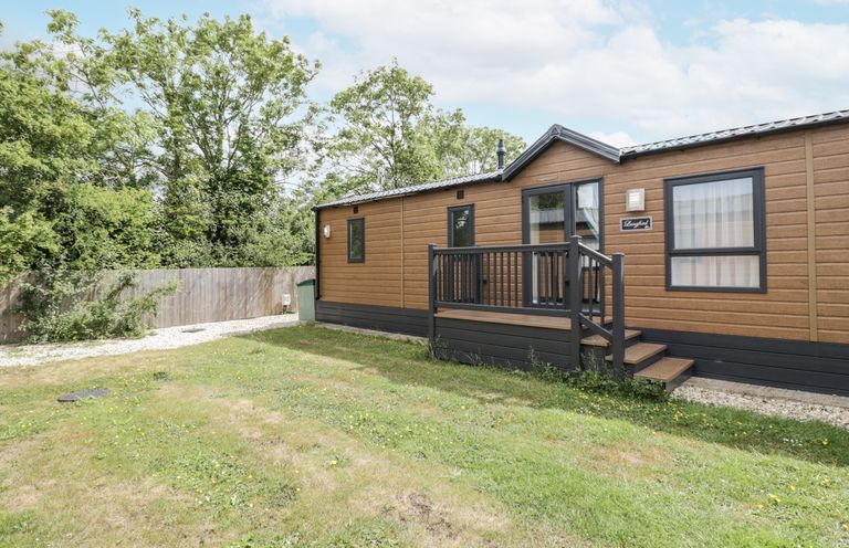 A mobile home with a deck surrounded by grass at Serendipity