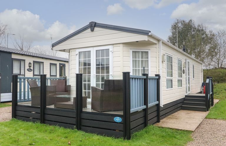 A static caravan with a glass enclosed patio and outdoor seating at The Bobbin Number 11 in South Lakeland Leisure Village near Carnforth