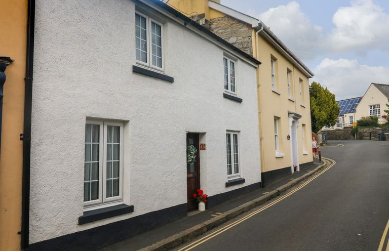 A street view with white and yellow houses along a curved road with double yellow lines at Hope Cottage in Buckfastleigh