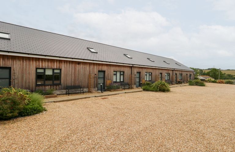 An outdoor area with a wooden building and gravel pathway at Dirdale in Weymouth