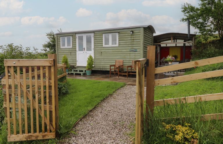 A shepherd's hut with a pathway and gate at The Journeyman Luxury Shepherds Hut in Barnoldswick