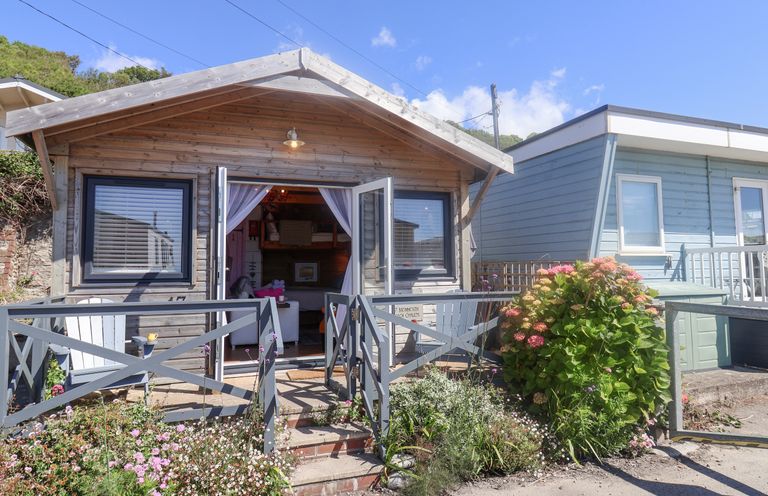 A wooden cabin with open doors and a small garden in front at Sea Spray in Lyme Regis