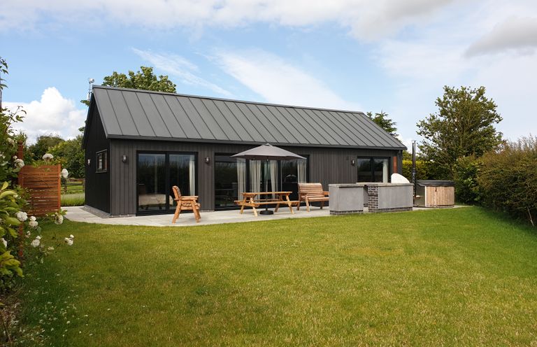 A backyard with lawn umbrella wooden chairs picnic table and hot tub at Skylark in Bishop Wilton