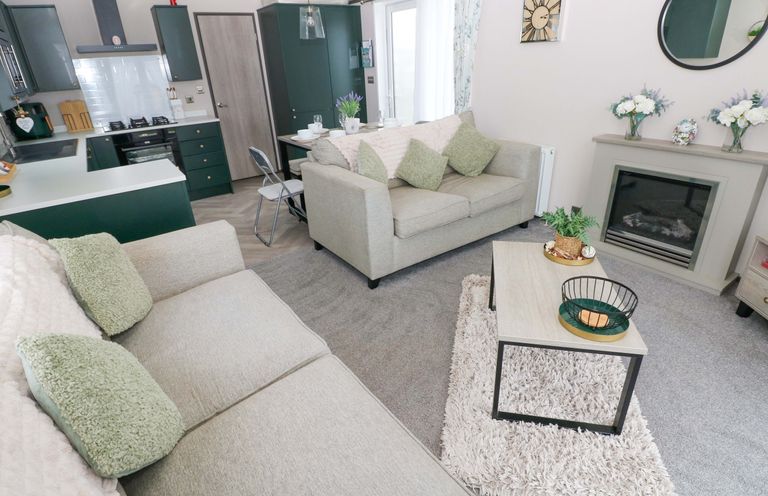 A living room with a fireplace and coffee table at Oyster Lodge in Little Haven