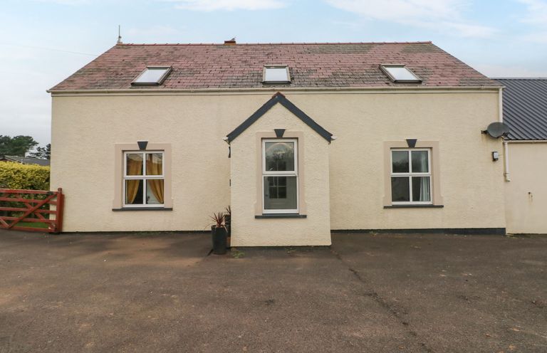 A beige house with three windows and three skylights on a paved area at Ocean House in Broad Haven