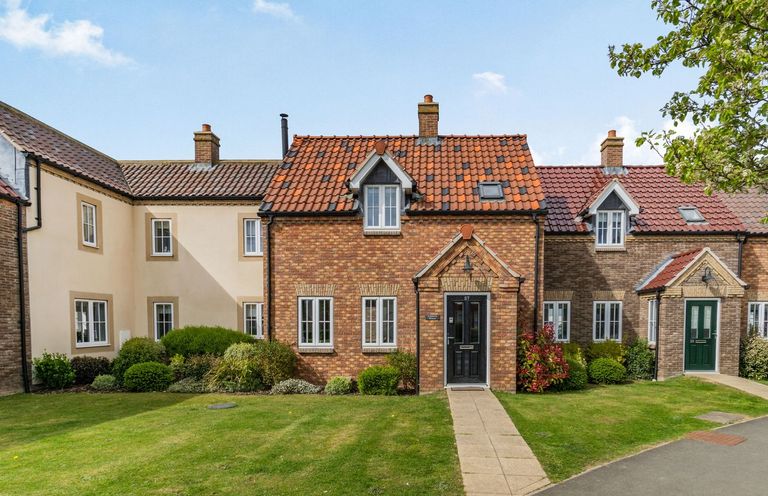 A row of brick and plaster houses with tiled roofs and front gardens at Lantern House in Filey