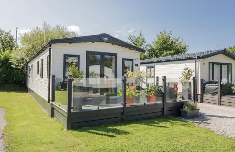 A mobile home with a porch and plants at Lilac Lodge Carnforth