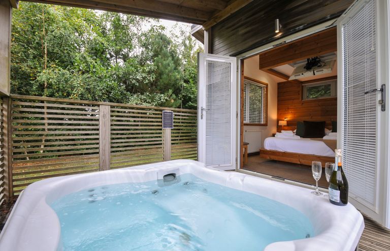 A hot tub with outdoor decking and a bed visible through a sliding door at 3 Southern Place Dobwalls