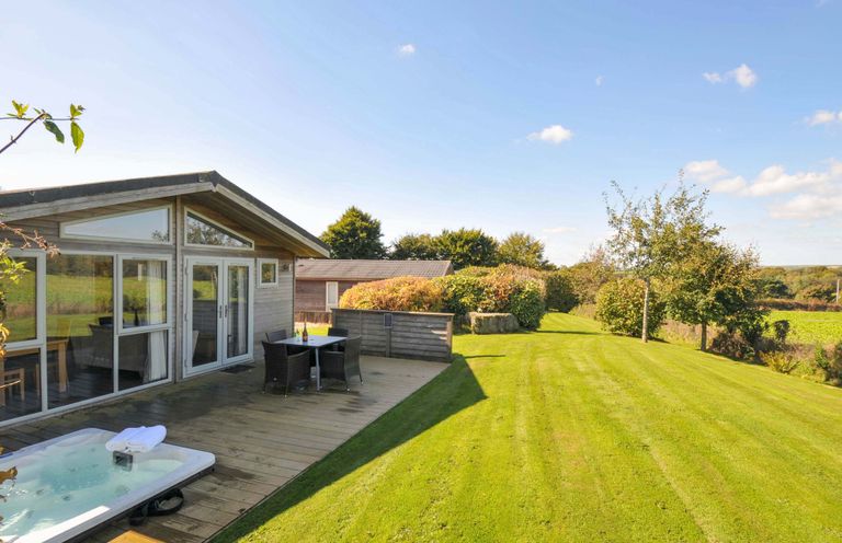 A garden with a deck, hot tub, table, and chairs at 3 Horizon View in Dobwalls