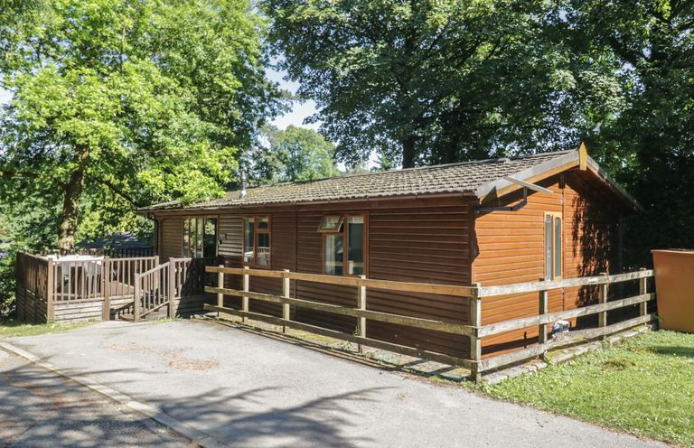 A cabin with decking and trees at Treetops, Beech Hill 13, Fallbarrow Park near Bowness-On-Windermere