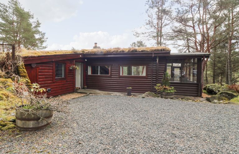 A one-story cabin with a grass-covered roof surrounded by trees at Rocksite in Kirkmichael Perth And Kinross