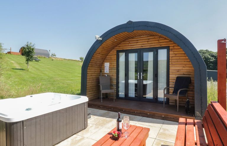 An outdoor area with a hot tub and wooden cabin at Rowan in Ulverston