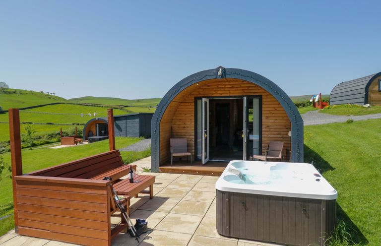 An outdoor area with a hot tub and wooden bench at Cherry in Ulverston