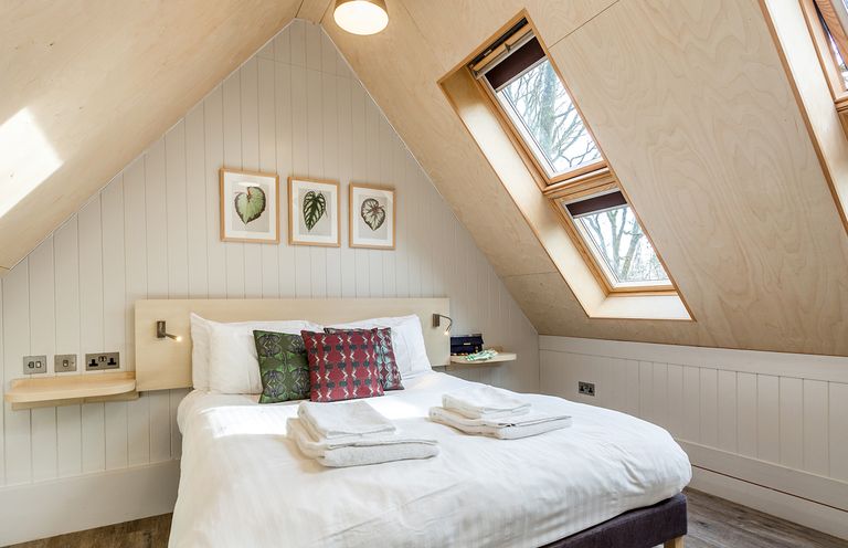 A bedroom with a bed pillows towels and three framed pictures on the wall at Lodge 9 in Corfe Castle