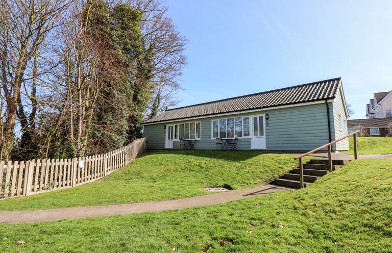 A single-story building with a tiled roof lawn and trees at 15 The Dell in Mundesley