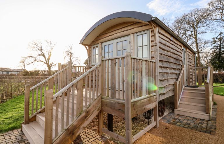 An exterior view of a wooden cabin with two sets of stairs and a small porch at Amy Johnson in Bolton Percy near Tadcaster