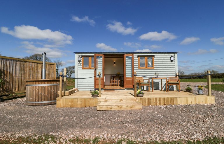 A small cabin with wooden deck and outdoor seating with hot tub outside at Buzzards in Morchard Bishop