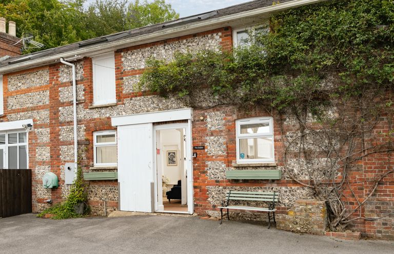 An exterior view of a building with a door and bench at The Stable in Blandford Forum
