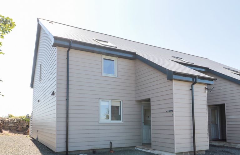 Exterior view of a beige two-story house with a sloped roof and multiple windows at Thrift Lodge in High Newton-by-the-Sea near Embleton