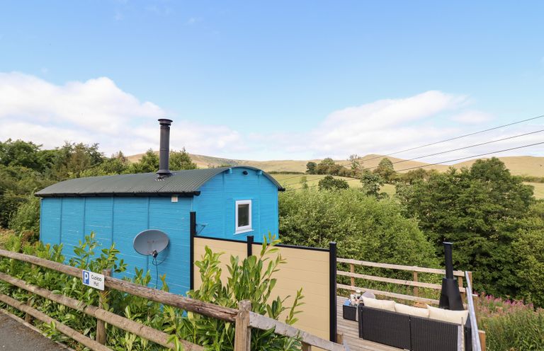 A hut and deck with trees in the background at Cuckoo at Wild Valley Huts Llanrhaeadr-Ym-Mochnant
