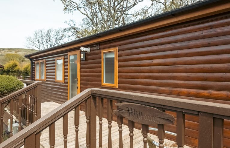 A wooden cabin exterior with a deck and steps at Willow in Swanage