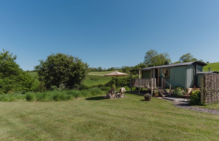 A garden with a mobile home and deck at Hurdlemakers Hut in Piddletrenthide