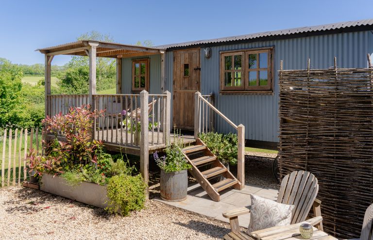 An outdoor hut with steps and planters at Spindleberry Hut in Piddletrenthide