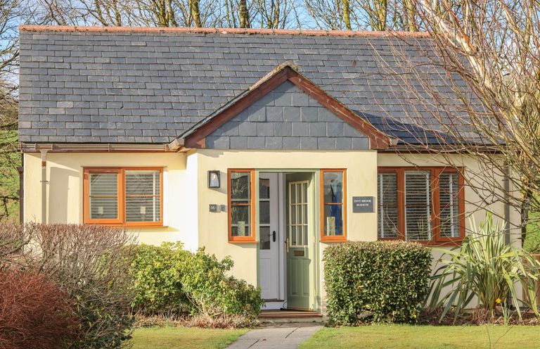 A small house with a grey tiled roof green front door and bushes in front at Inny Brook Burrow Davidstow near Camelford