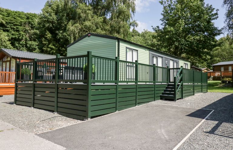 A mobile home with green railing and steps surrounded by trees at 43 Pony Meadow in Troutbeck Bridge