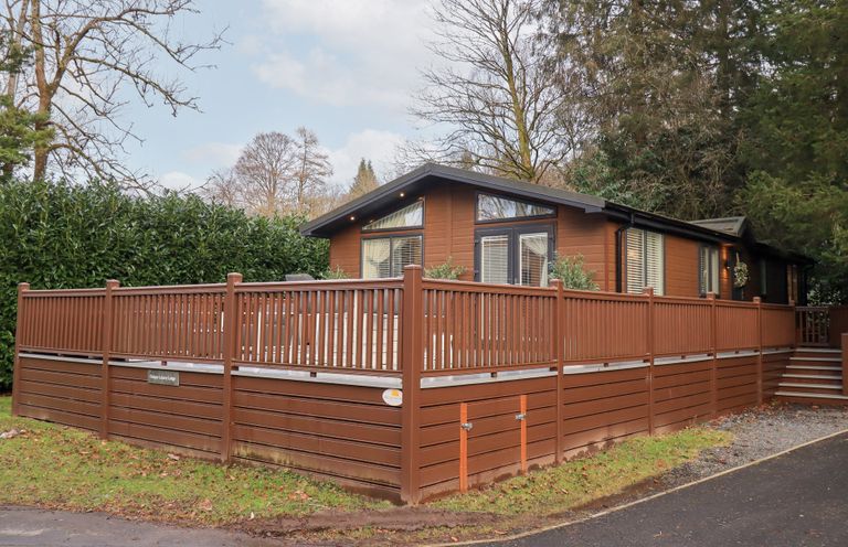 A lodge with a wooden deck and railings at Unique Luxury Lodge 1 Langdale, White Cross Bay near Windermere