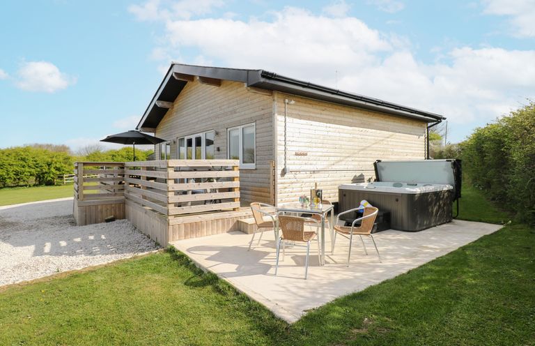 An outdoor patio with a hot tub and seating area at Heritage Retreat Monknash