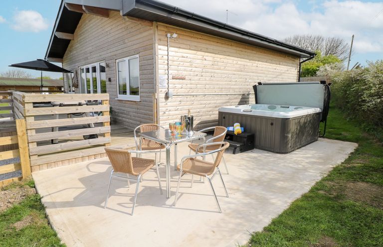 An outdoor area with a hot tub and seating at Monks Rest in Monknash