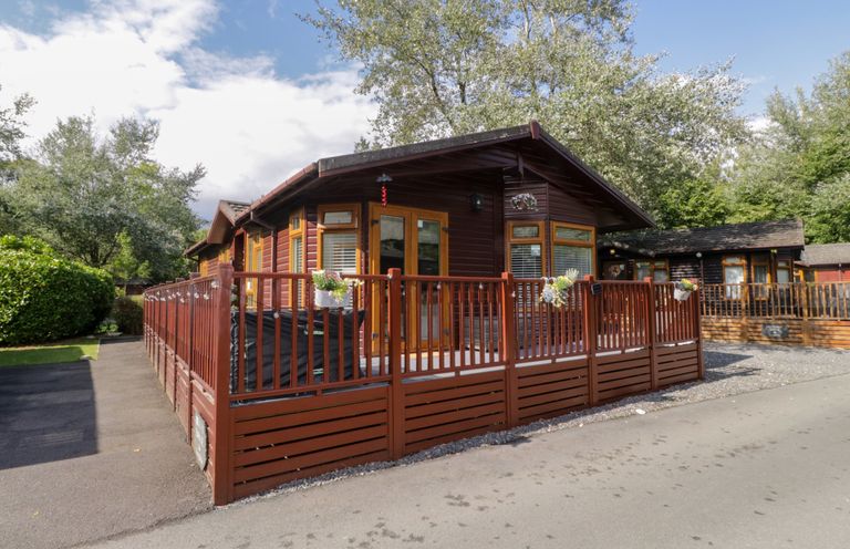 A lodge with a wooden deck and fence at Ruskin Lodge, Langdale 16, White Cross Bay near Windermere
