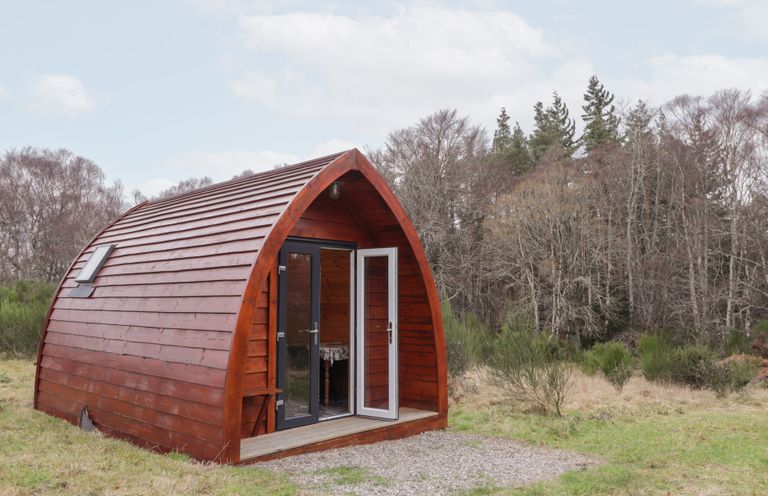A wooden cabin with a door and windows in a natural setting at Pod 1